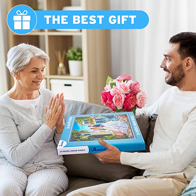 Two adults with a boxed Spring Wedding puzzle and pink flowers beneath a “The Best Gift” banner — Assistex via EOWD Autism Living