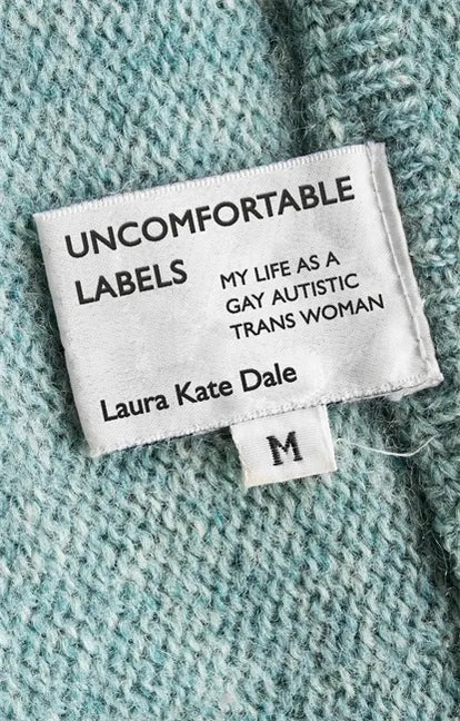 Paperback cover of Uncomfortable Labels by Laura Kate Dale — clothing label sewn into teal fabric reading "my life as a gay autistic trans woman" — Books by splitShops via EOWD Autism Living